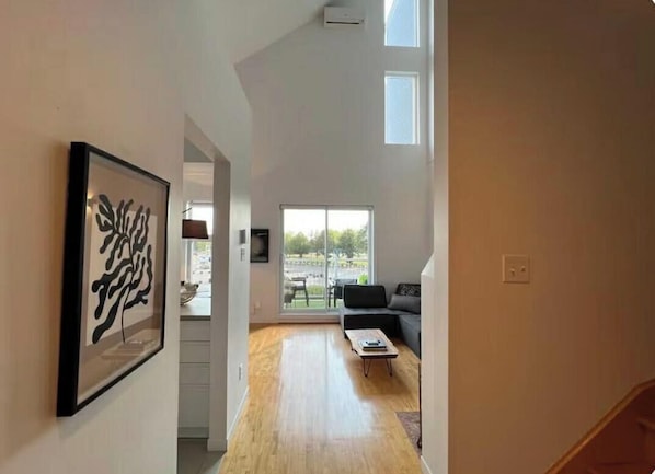 Un intérieur moderne avec un plancher en bois, un canapé, une table basse et une grande fenêtre.