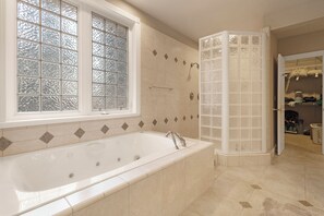 A bathroom with a freestanding bathtub, a window with frosted glass, and a shower enclosure with frosted glass panels.