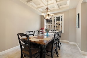 A dining area with a wooden table, black chairs, a chandelier, and a window with a view of a rocky landscape. - Marvelous 4-bedroom villa with AC in charming Chester. Lake Almanor Home (Chester)