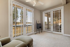 A room with a large sliding glass door leading to a deck, a ceiling fan, and a framed picture on the wall.