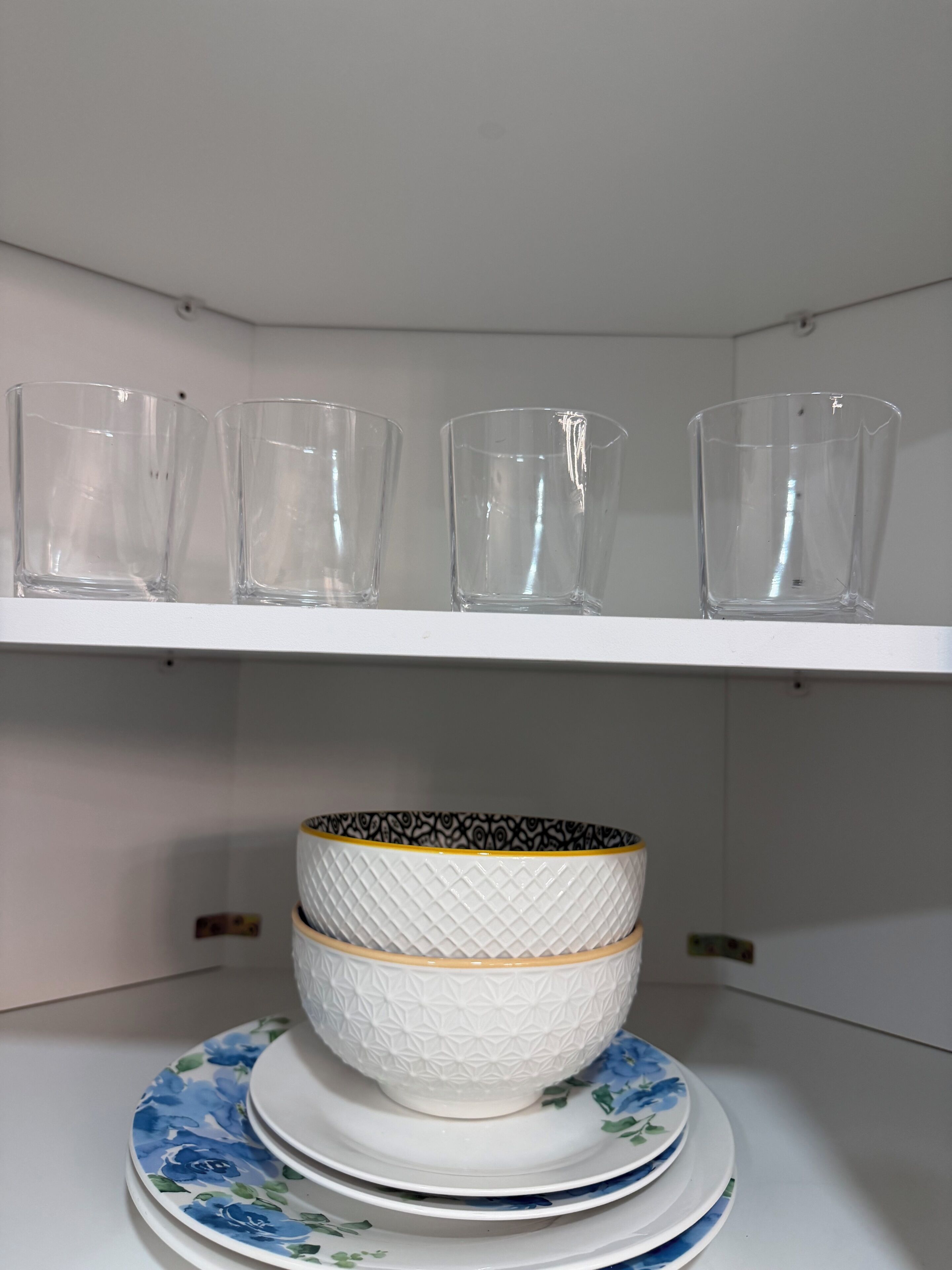 A shelf with clear glassware and a decorative bowl with a patterned bowl and matching plate.