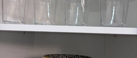 A shelf with clear glassware and a decorative bowl with a patterned bowl and matching plate.