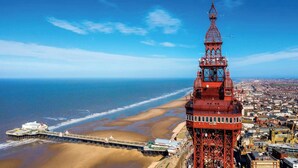 A coastal cityscape with a prominent red tower structure, a pier extending into the sea, and a beach. - Caravan Sleeps 5 - Decking, Parking, Pet Friendly (Blackpool)