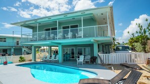 A two-story house with a swimming pool, outdoor furniture, and a fenced yard. - Marathon Oceanfront 4BR, 3.5BA Private Pool 60’ Boat Dock (Marathon)