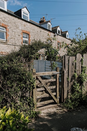 A stone house with a wooden gate, a clear sky, and a fence. - Charming 2-bedroom cottage with countryside views (Weymouth)