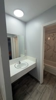 Un baño con lavamanos blanco, un espejo y una bañera.