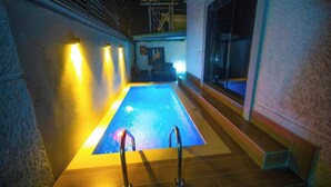 En swimmingpool med en stege, omgiven av väggar och ett fönster.