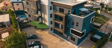 Un edificio residencial de varios pisos con estacionamiento, techo verde y estilo arquitectónico moderno.