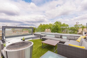 Terraço no telhado com estrutura de vidro, área de estar externa e churrasqueira.