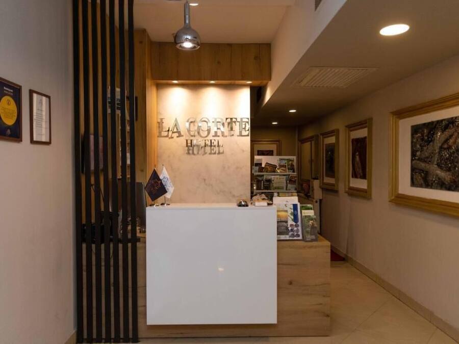 Una mesa de recepción con un cartel que dice 'La Corte Hotel' y certificados enmarcados en la pared.