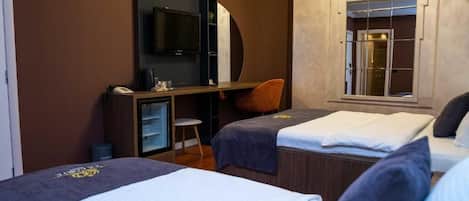 Ein Hotelzimmer mit zwei Betten, einem Schreibtisch mit Stuhl, einem Fernseher und einem großen Spiegel.
