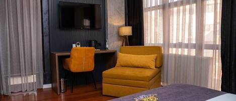 A hotel room with a bed, a desk, a chair, a TV, and a window with curtains.