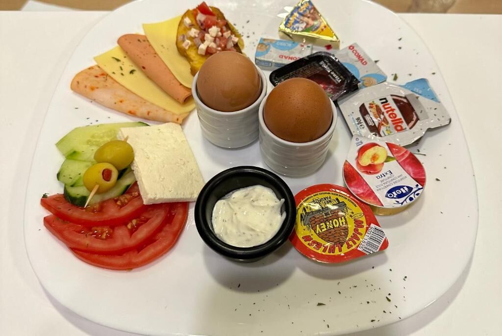 Un plato con diferentes alimentos, como huevos, queso y salsas.