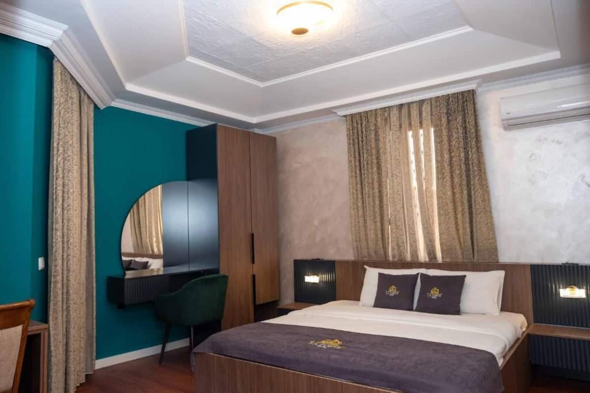 Une chambre d’hôtel comprenant un lit, un bureau, une chaise, une armoire et un miroir.