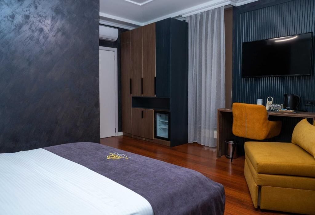 Una camera d'albergo con un letto, una scrivania, una televisione e un divano.