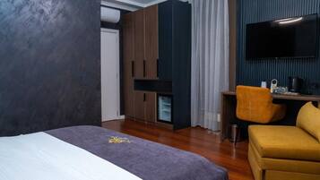 Una camera d'albergo con un letto, una scrivania, una televisione e un divano.