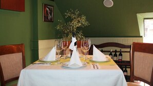 Una mesa de comedor dispuesta con copas de vino, platos y un centro de mesa.