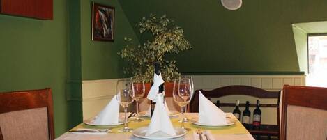 Une table à manger dressée avec des verres à vin, des assiettes et un centre de table.
