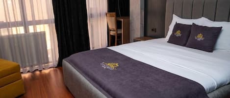 A hotel room with a bed, a desk, and a chair.