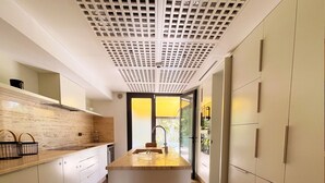 A modern kitchen with a central island, white cabinetry, and a ceiling with a grid pattern. - Carthage Villa 3BR Luxury Pool Garden (Carthage)