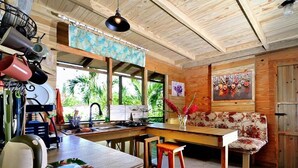 Una cocina con techo de madera, una zona de comedor con banco y vistas al exterior.