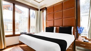 Habitación de hotel con una cama grande, piso de madera, cabecera acolchada y vistas a edificios.