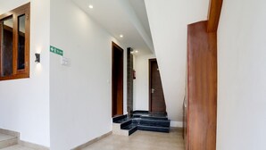 Un pasillo con una escalera que lleva a una puerta señalizada con 'EXIT', un extintor y un cartel que indica la ruta de evacuación.