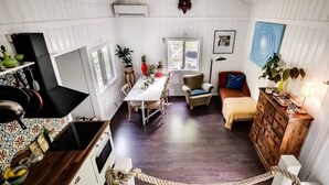A cozy room with a dining table, a chair, a sofa, a dresser, and a clock on the wall. - Ekhaga Cabins - Holiday home by the Baltic Sea with sauna & nature (Dröstorp)