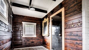 A room with wooden walls, a tiled floor, a window, and a door with a mirror. - Ekhaga Cabins - Holiday home by the Baltic Sea with sauna & nature (Dröstorp)