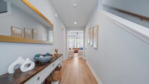 Un couloir avec un banc en bois, un miroir et des œuvres d’art encadrées accrochées aux murs.