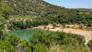A natural landscape with a lake, trees, and a hill.