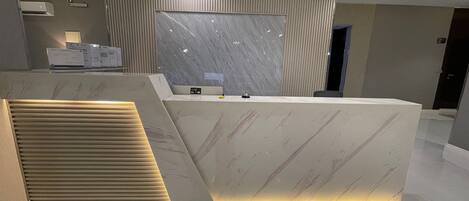 Una recepción con encimera de mármol, panel de control y diseño moderno.