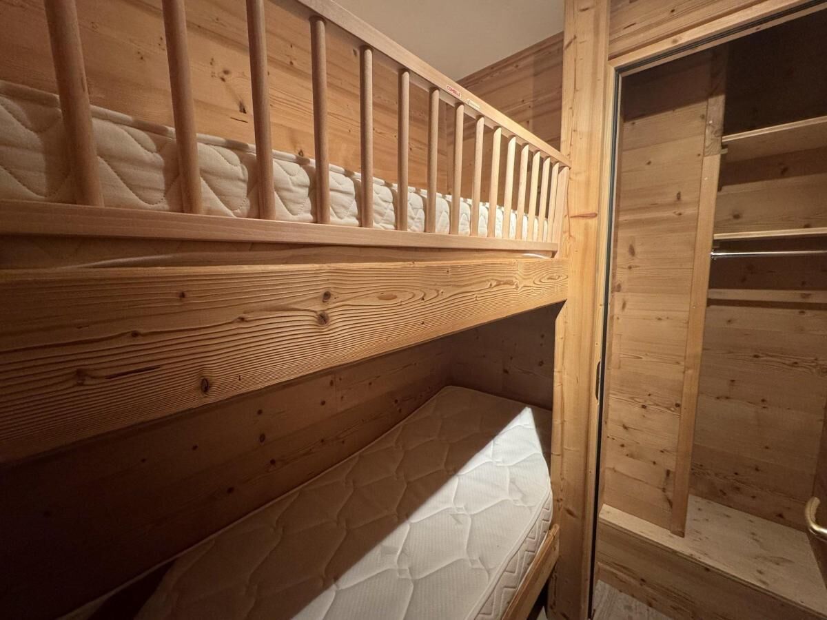 A bunk bed with a wooden headboard and a lower bunk with a mattress.