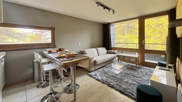 Una sala de estar moderna con sofá, mesa de comedor y televisor.