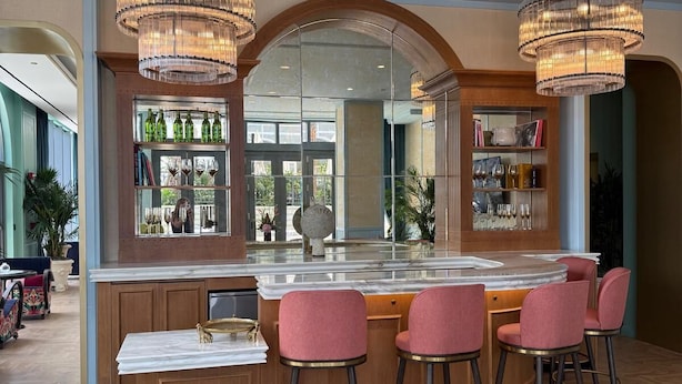 A bar area with a marble countertop, bar stools, and a large mirror. - Stylish Residences Wynwood (Miami)
