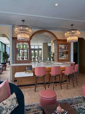 Un espace bar dotĂ© dâun comptoir en marbre, de tabourets de bar et dâun grand miroir.