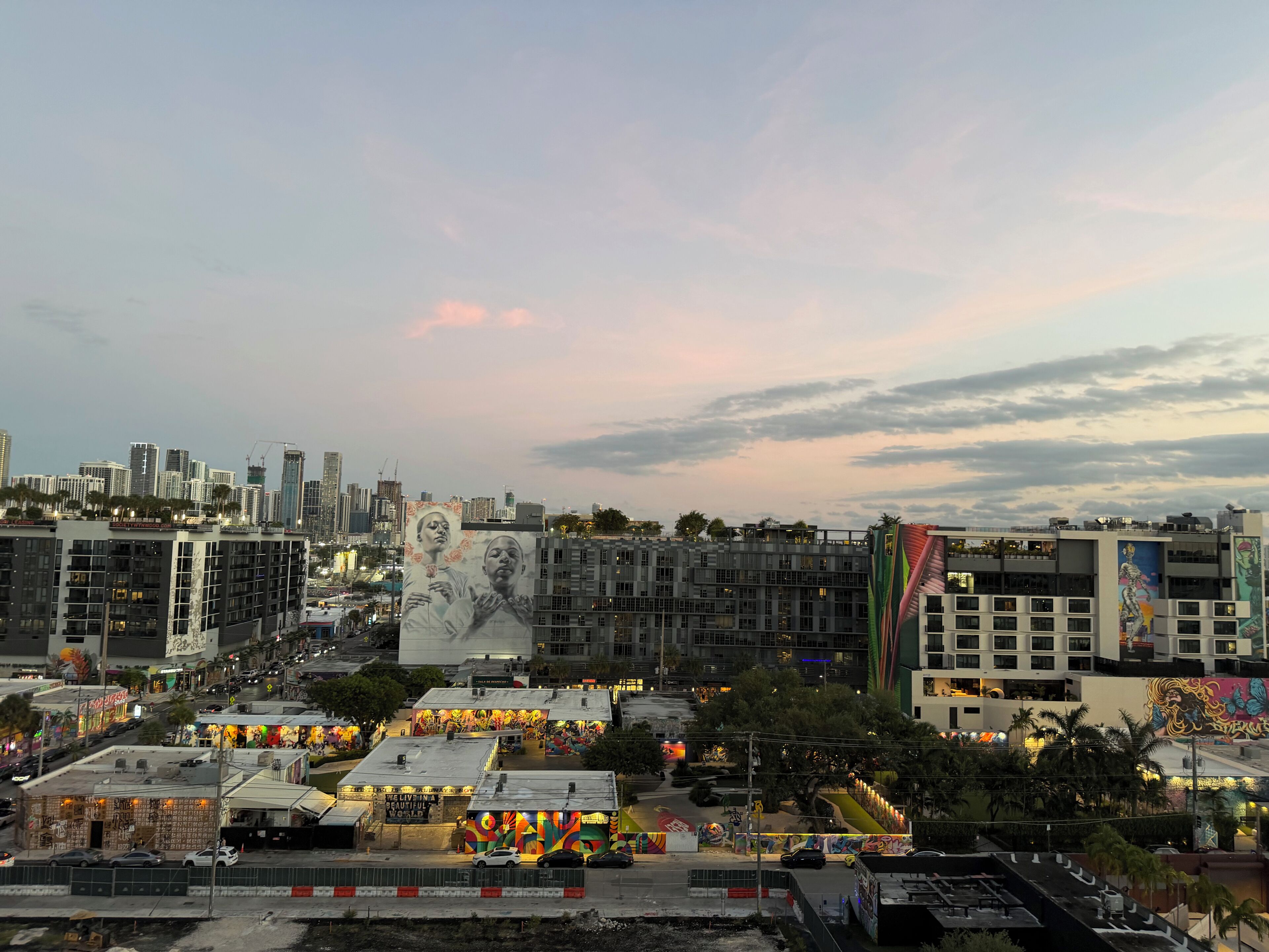 A cityscape with modern buildings, a mural, and a busy street.