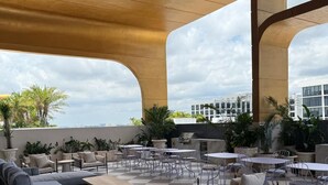 An outdoor patio area with checkered flooring, metal furniture, and large structural beams overhead. - Stylish Residences Wynwood (Miami)