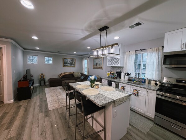 A modern kitchen with a central island, built-in appliances, and a dining area with a sofa and coffee table.