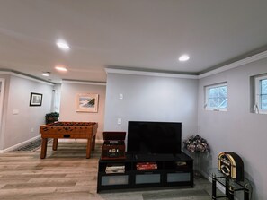 A living room with a foosball table, a television, and a jukebox.