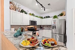 Eine moderne Küche mit weißen Schränken, einem Edelstahl-Kühlschrank und einer Arbeitsplatte aus Granit.