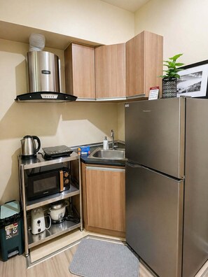 Eine kleine Küche mit Edelstahlkühlschrank, Mikrowelle, Wasserkocher, Kaffeemaschine und Spüle.