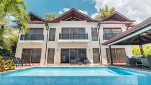 Un edificio de dos pisos con piscina, balcones y un patio cubierto.