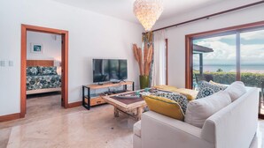 Una sala de estar moderna con televisor, sofá, mesa de centro y un ventanal con vistas.