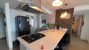Een moderne keuken met een centraal eiland, een inbouwfornuis en hanglampen.