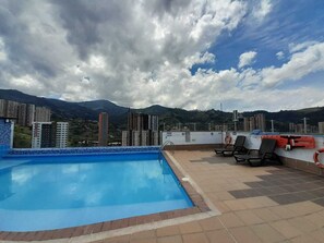 Ein Pool auf dem Dach mit Blick auf umliegende Gebäude und Berge.