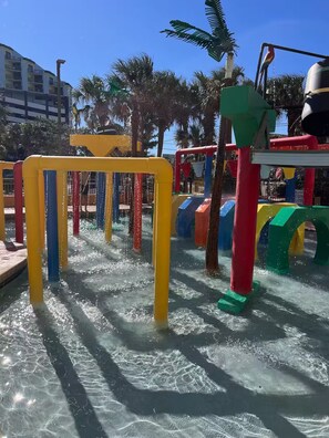 Ein Wasserspielbereich mit bunten Bauwerken und Palmen im Hintergrund.