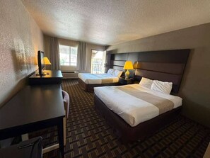 Ein Hotelzimmer mit zwei Betten, einem Schreibtisch und einem Stuhl.