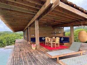 A wooden deck with a pool, outdoor seating, and a view of the mountains. - Punta Pájaros Villa 9 Puerto Escondido, Oaxaca (Puerto Escondido)