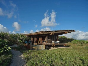 Une structure moderne, à ciel ouvert, dotée d’un grand toit en surplomb, d’une piscine et d’un chemin menant à l’entrée.